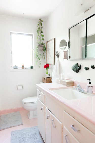 pink bathroom vanity with pink tile countertop, undermount ceramic sink with silver faucet, pink tile floor, white toilet, window, rectangular medicine cabinet