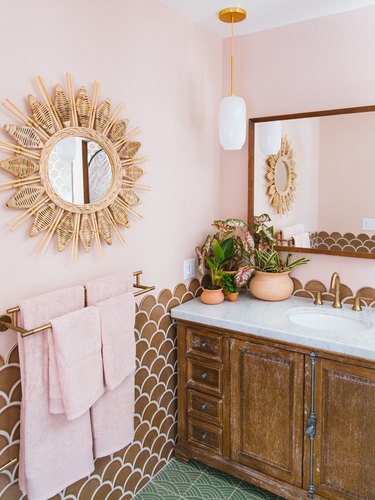 pink bohemian bathroom lighting idea with brown tiles, rattan details and gold pendant lighting