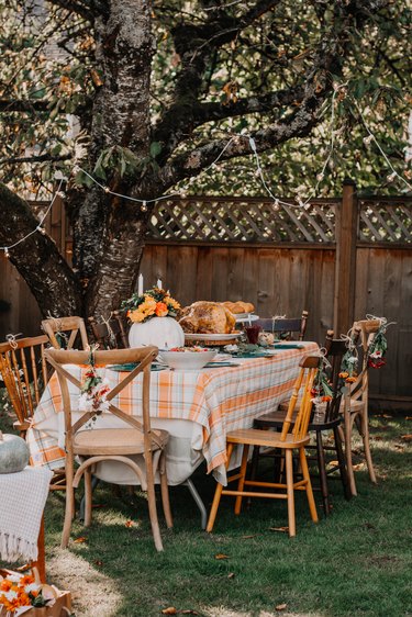 outdoor fall party idea with plaid tablecloth and string lights