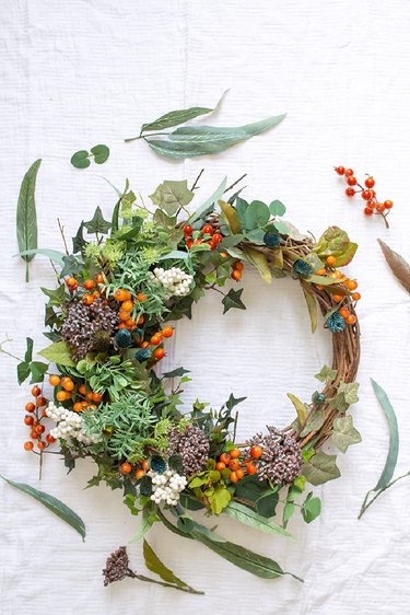 fall wreath made with foraged greens, berries, and dried flowers
