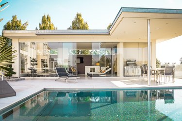 house with glass walls and pool nearby