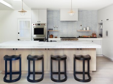 Modern coastal kitchen ideas with black bar stools and wood and marble island
