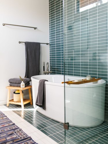 midcentury bathroom with horizontal stacked teal tiles and white pill-shaped bathtub