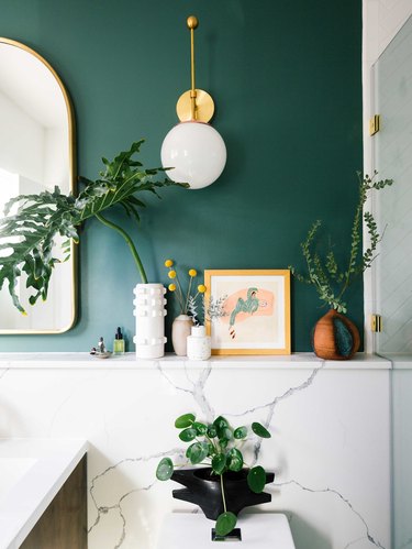 midcentury bathroom lighting idea with wall sconces on green walls and marble backsplash