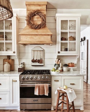 fall kitchen decor in white kitchen with stool and wreath on stove range