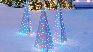 exterior Christmas decorations with Multi colored lights inside modern Christmas trees outside on patch of snow.