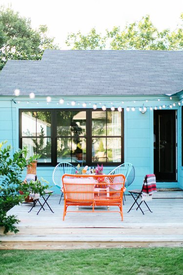 Turquoise blue exterior beach house colors with string lights and outdoor sitting area