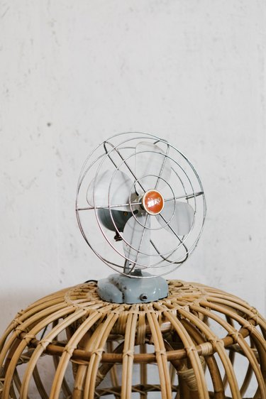 Small oscillating fan on rattan side table