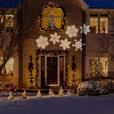 exterior Christmas decorations with Traditional Christmas decor on front of home with projection snowflake lights.