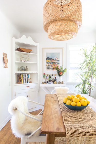 white dining room with woven rattan pendant light
