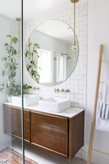 bathroom with white tile backsplash and vessel sinks ant potted plant on floating vanity