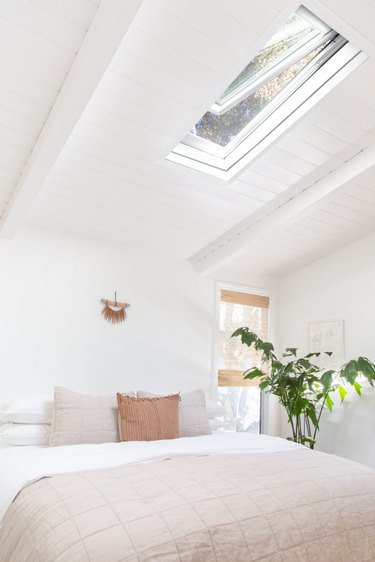 White minimalist coastal bedding idea with cream bedding and skylight