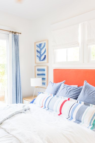 Classic coastal bedding idea with orange headboard and striped lumbar pillow