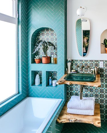 glass bathroom sink with patterned tile and wood countertop