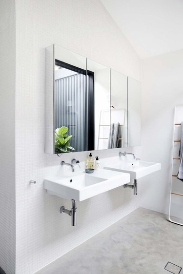 A pair of white wall-mounted bathroom sinks in a modern space with concrete flooring