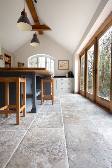limestone kitchen flooring with wood accents and blue island