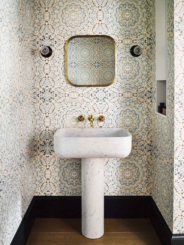Modern bathroom pedestal sink made from marble with wallpaper on walls