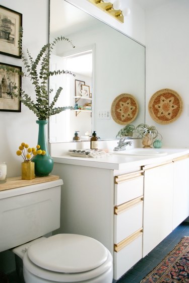 self-rimming bathroom sink in a boho rental with frameless mirror and white vanity cabinet