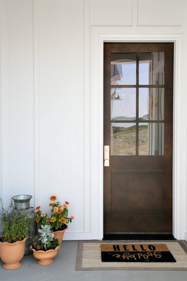 White exterior paneling surrounding wood finish front door