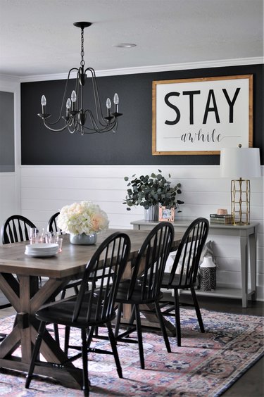 dark farmhouse dining room with iron chandelier and white shiplap walls