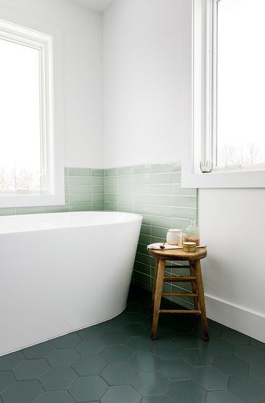 Green subway tile coastal backsplash surrounding white bathtub