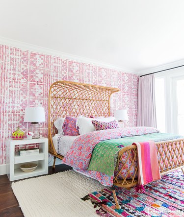 pink bohemian bedroom with woven rattan bed and pattern wallpaper