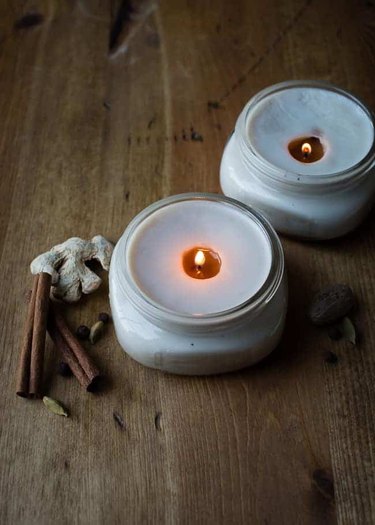 DIY fall decor idea with lit white candles on wood floor