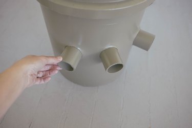 Pushing three short PVC pipes through the holes in bucket