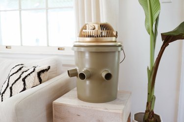 Green and gold portable bucket air conditioner on an end table next to a couch