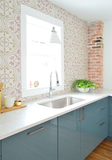 Pink and white floral coastal backsplash in kitchen with blue cabinets