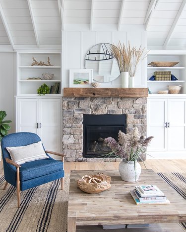 Coastal fall decor in coastal style living room with stonework fireplace and dried grasses