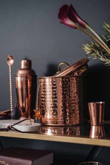 Copper barware, including ice bucket, cup, and mixer.