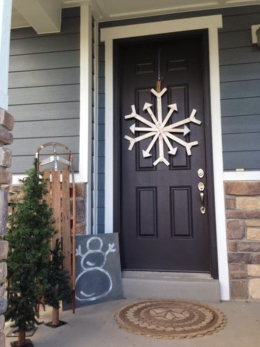 Christmas Door Decorations on Black front door with hand made snowflake, chalk board with snowman, small Christmas tree.