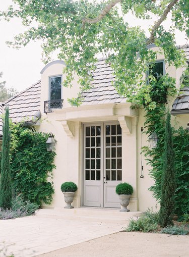 French country exterior with French doors and lush greenery
