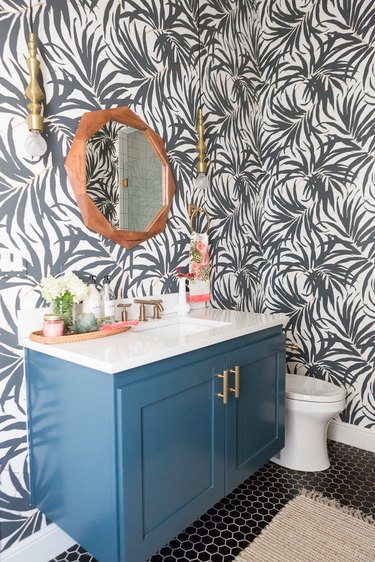 Beachy bathroom wallpaper with black and white palm print and blue vanity cabinet