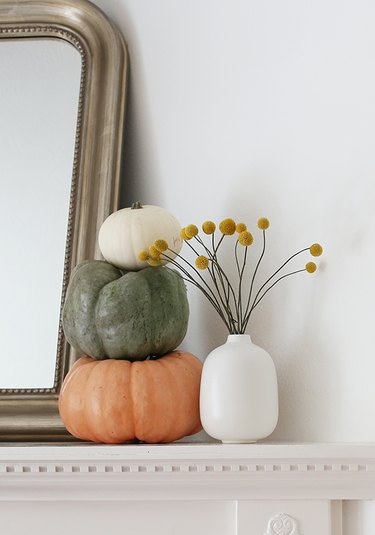 modern fall decor on fireplace mantel with stack of pumpkins on the mantel