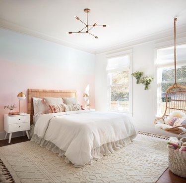 pink ombré wall in little girls bedroom with hanging chair and kids nightstand