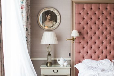 pink bedroom with tufted headboard and pink wallpaper