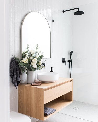 Black handheld showerhead and rain shower in white modern bathroom