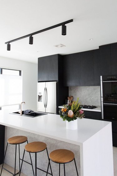 track style kitchen ceiling lights over island with black cabinets and