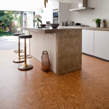 kitchen space with white and neutral cabinets and cork flooring