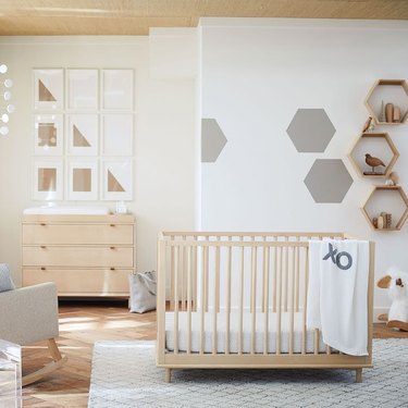 baby nursery design with light wood furniture and hexagon shaped shelving on wall