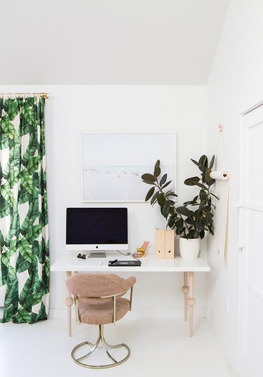 small home office with to-do list on display with paper on the wall and tropical drapery