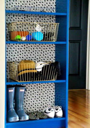 Blue bookcase with polka dot wallpaper lining the back
