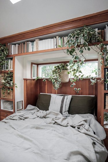 small bedroom with built-in shelving and greenery