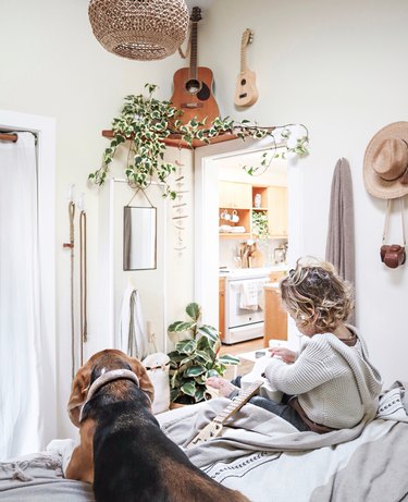 small bedroom with corner shelf displaying guitar and plants