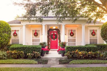 Traditional Christmas yard decorations with wreaths and red door