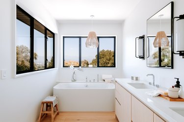 White and wood bathroom with natural pendant light over white bathtub.