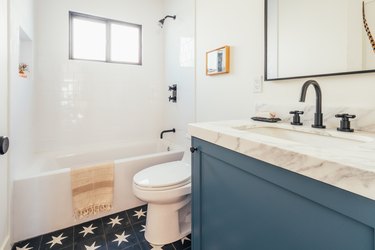 Bathroom with blue and white star tile floor and marble countertop on blue painted sink