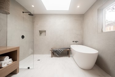 Modern bathroom with large tub and shower, skylight, recessed lights.